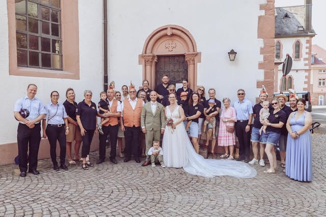 Hochzeitsgesellschaft mit Mitgliedern der Wasserschnecken vor einer Kirche