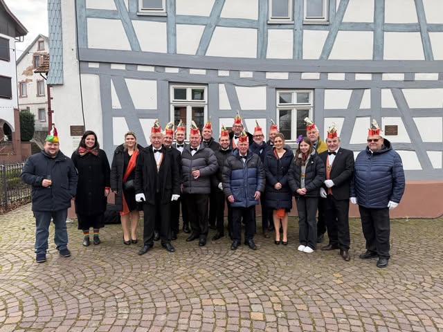 Wasserschnecken in Fastnachtskappen vor einem Fachwerkhaus